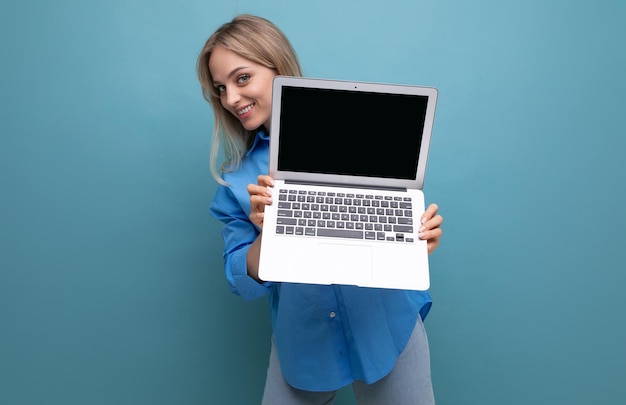 Süßes glückliches blondes Mädchen zeigt offene Notizbücher mit Leerraum für Webseite auf blauem Hintergrund