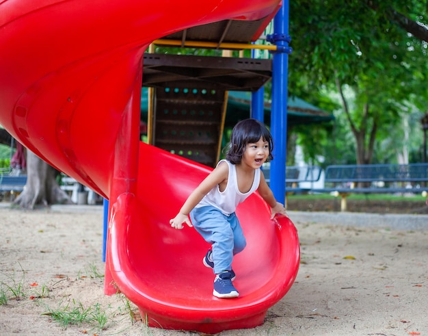 süßes kind, das rutsche auf dem spielplatz spielt