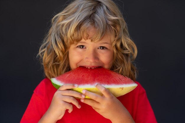 Süßes Kind isst Wassermelone Kind pflückt Wassermelone auf grauem Hintergrund