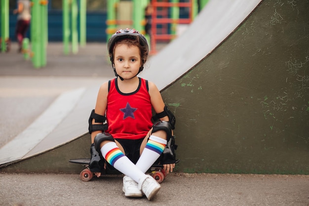 Süßes Kind Mädchen mit Skateboard in der Nähe der Grunge-Wand Sommersport-Aktivitätskonzept