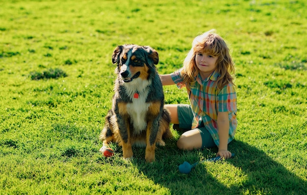 Süßes Kind mit einem Hündchen im Sommer im Freien Der Junge spielt im Sommer mit dem Hund im Park