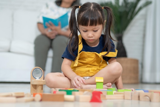 Süßes kleines asiatisches Mädchen, das mit bunten Spielzeugblöcken spielt Kinder mit Lernspielzeug im Kindergarten