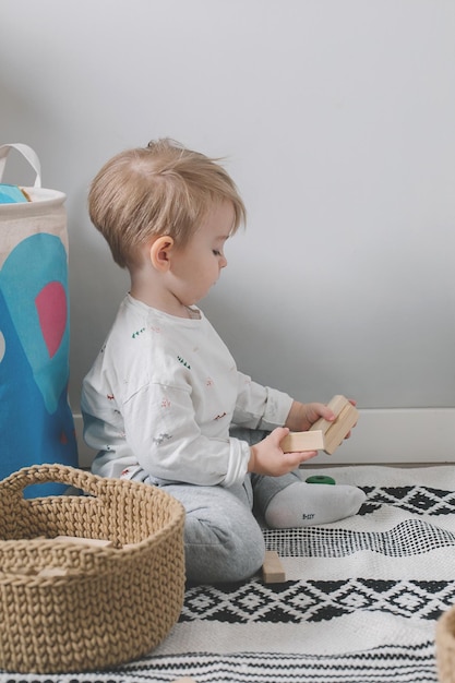 Süßes kleines Kind, das zu Hause mit Holzspielzeugblöcken auf dem Boden spielt Öko-Spielzeug für Kinder ohne Abfall