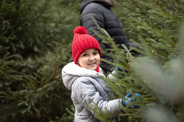 Süßes kleines Kind wählt mit seiner Familie frisch geschnittenen Weihnachtsbaum im Freien