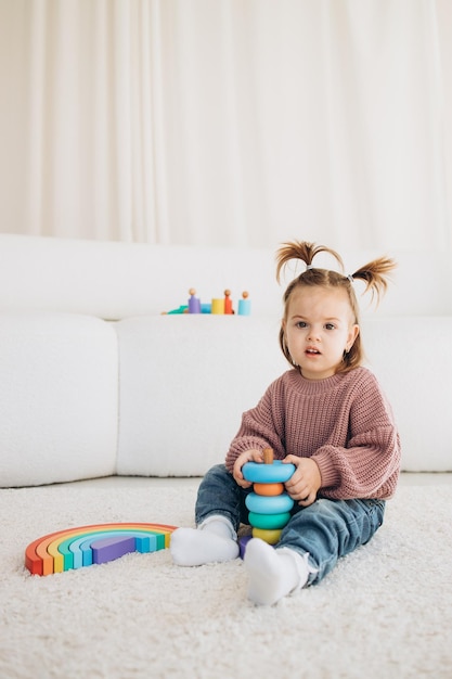 Süßes kleines Kleinkind, das zu Hause mit Öko-Holzspielzeug spielt Glückliches Kind, das Gemüse und Obst mit Spielzeugmesser schneidet Das Kind spielt Lernspiele