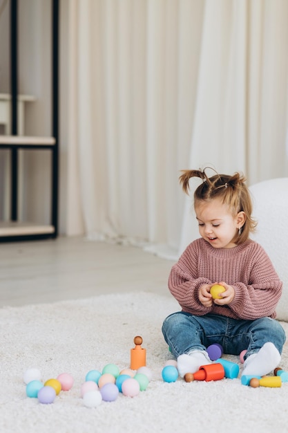 Süßes kleines Kleinkind, das zu Hause mit Öko-Holzspielzeug spielt Glückliches Kind, das Gemüse und Obst mit Spielzeugmesser schneidet Das Kind spielt Lernspiele