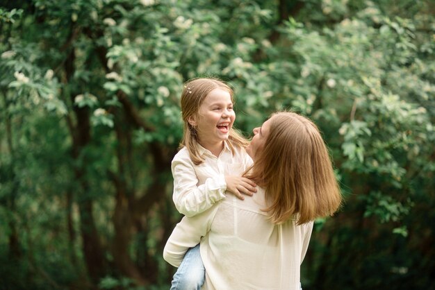 Süßes kleines Mädchen 4 Jahre alt und ihre schöne Mutter gehen im Frühling im Park spazieren