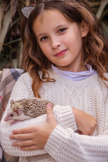 süßes kleines Mädchen, das einen Igel in den Armen hält Herbstporträt