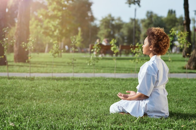 Süßes kleines Mädchen Karateka macht Meditationsübung im Freien