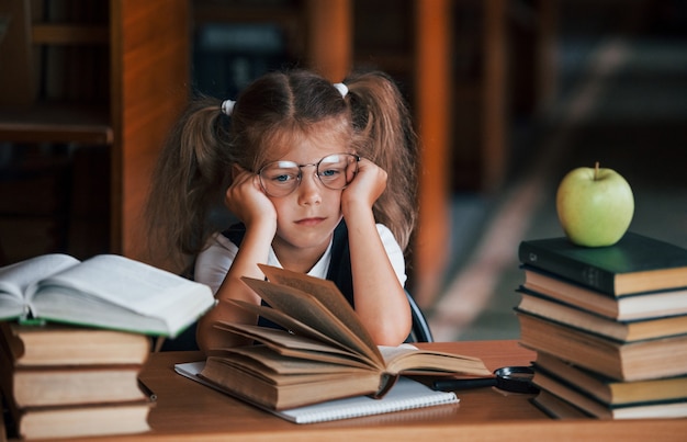 Süßes kleines Mädchen mit Zöpfen ist in der Bibliothek