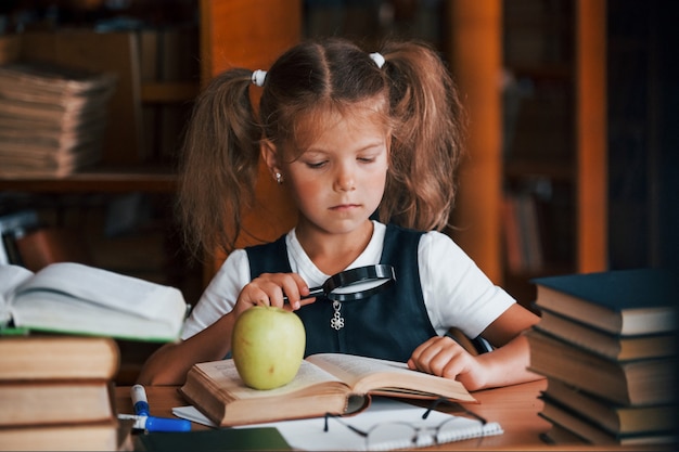 Süßes kleines Mädchen mit Zöpfen ist in der Bibliothek