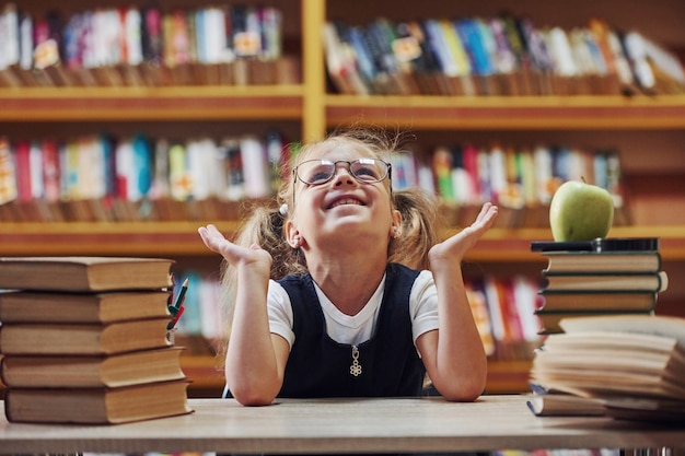 Süßes kleines Mädchen mit Zöpfen ist in der Bibliothek