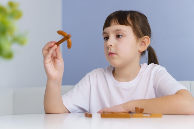 Süßes kleines Mädchen spielt zu Hause mit Holzpuzzleblöcken Entwicklungs- und Bildungskonzept für Kinder