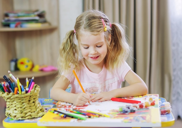 Süßes kleines Mädchen zeichnet zu Hause mit Bleistiften und Filzstiften