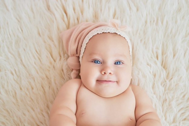 Süßes lustiges Baby auf dem Bett im Kinderzimmer. Süßes Baby 6 Monate sitzend und kriechend.