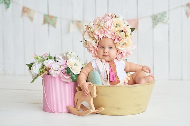 Süßes lustiges Baby im Hut mit Blumen. Ostern. Nettes Baby 6 Monate, das Blumenhut trägt.