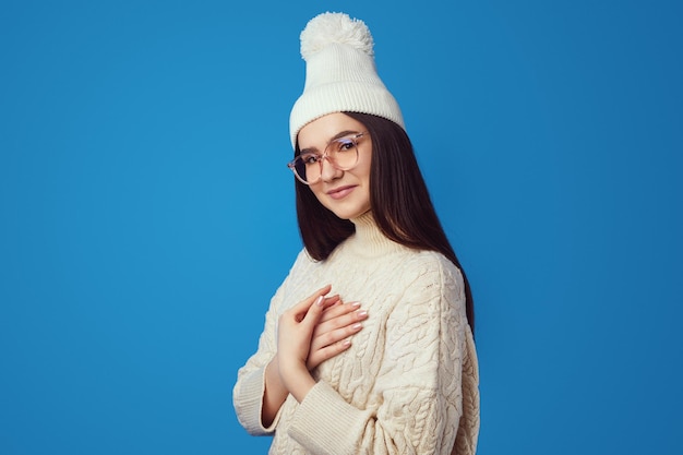 Süßes Mädchen berührt Herz mit beiden Handflächen drückt großes Mitgefühl aus und fühlt Liebe