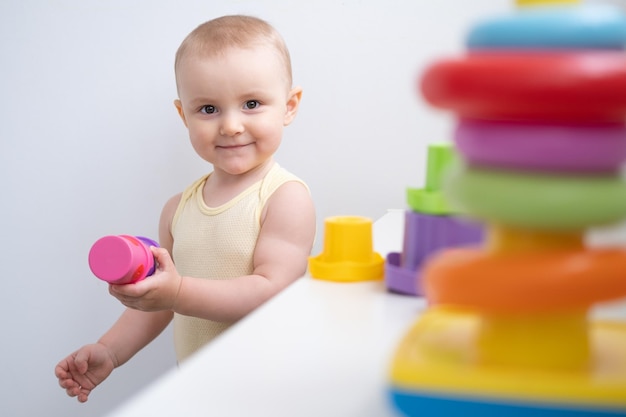 Süßes Mädchen, das zu Hause in bunten Plastikspielzeugen spielt Frühkindliche Entwicklung