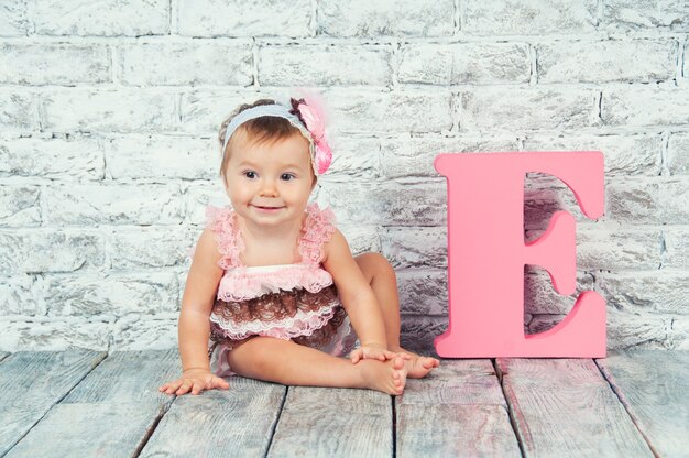 Foto süßes mädchen im rosa kleid mit dem buchstaben e.