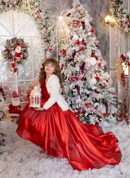 Süßes Mädchen in Erwartung des neuen Jahres und Weihnachten 2022 in einem eleganten Kleid mit Geschenken