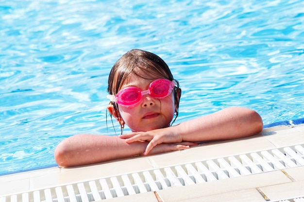 Süßes Mädchen in rosa Wasserbrille, das im Pool schwimmt und sucht