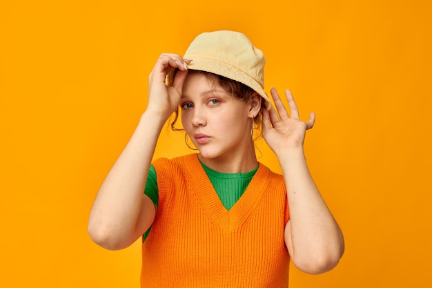 süßes mädchen mit hut, das orangefarbenen pullover aufwirft, isolierter hintergrund. Foto in hoher Qualität