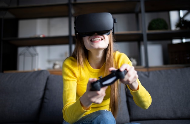 Süßes Mädchen spielt das Spiel auf der Konsole. Glückliche junge Frau, die ein Virtual-Reality-Headset verwendet