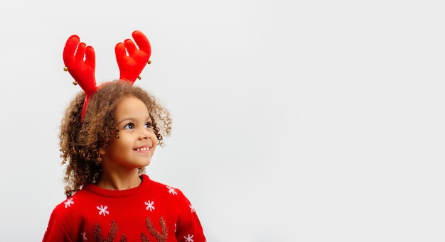 Süßes Rehkitz des afroamerikanischen Mädchens im roten Weihnachtspullover schaut weg auf weißem Hintergrund