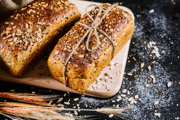 Süßes Roggenbrot und Weizen auf schwarzem Holzhintergrund