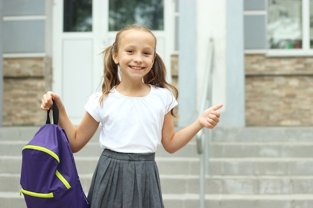 Süßes Schulmädchen mit Schulrucksack auf dem Schulhof