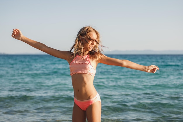 Süßes Teenager-Mädchen hat Spaß am Strand und schnappt sich die letzten Strahlen der Sonnenuntergangsonne.