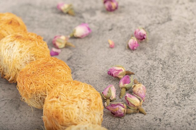 Süßes türkisches Dessert mit getrockneten Rosen auf Steinoberfläche.