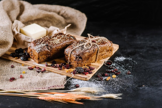 Süßes und leckeres Brot und Weizen auf schwarzem Holzhintergrund