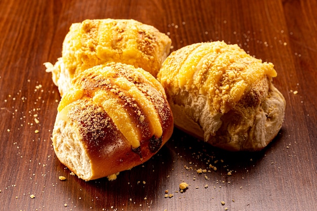 Süßes Vanillecremebrot und süßes Mehl auf einem braunen Holztisch. Es ist eine in Brasilien und Portugal übliche Brotsorte, die aus süßem Teig hergestellt wird.