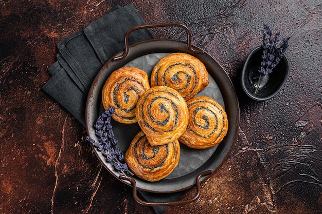 Süßes verdrehtes Brötchen mit Mohn und Lavendel Dunkler Hintergrund Ansicht von oben