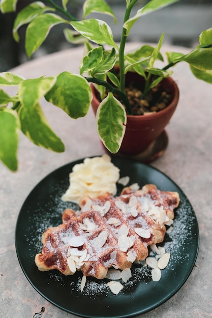 Süßes Waffel-Dessert auf dem Café-Tisch im Gartenhaus Frühstücksmahlzeit aus frischen, köstlichen Croissants und zuckergebackenen Gerichten