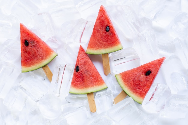 Süßes Wassermelonenscheibeneis am stiel auf Eishintergrund