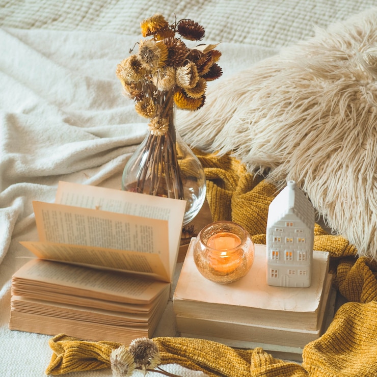 Foto süßes zuhause. stillleben details im innenraum des wohnzimmers. getrocknete blumenvase und kerze, herbstdekor auf den büchern. lesen, ausruhen. gemütliches herbst- oder winterkonzept.