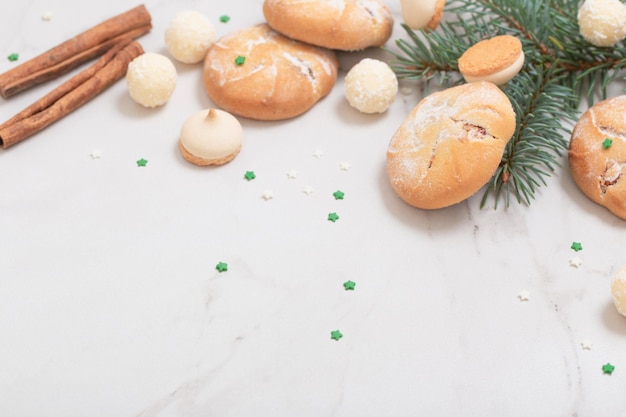 Süßigkeiten und Kekse mit Weihnachtsbaumzweigen auf weißem Marmorhintergrund