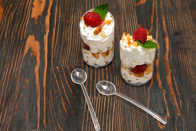 Süßspeise mit Schlagsahne, Nüssen und Himbeeren