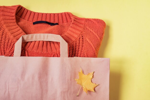 Foto suéter cálido mujer naranja en paquete de papel artesanal en amarillo