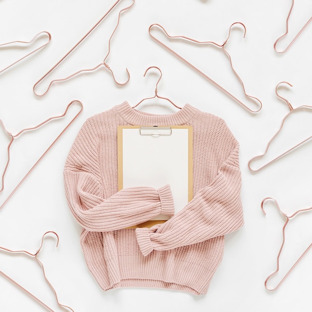 Suéter de malha rosa pálido com prancheta em fundo branco. Roupas de outono e inverno. Loja, venda, conceito de moda.