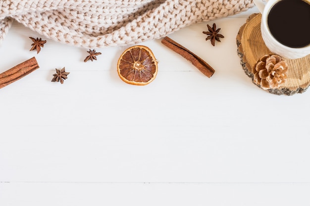 Suéter y elementos navideños, una taza de café sobre un fondo blanco de madera