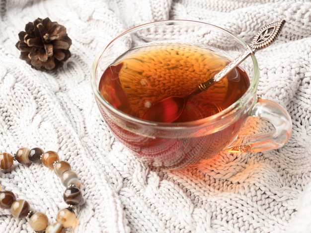 Suéter de punto cálido, una taza de té caliente con chocolate y decoraciones de invierno.