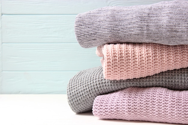 Suéteres de malha quentes dobrados em uma pilha sobre um plano de fundo claro