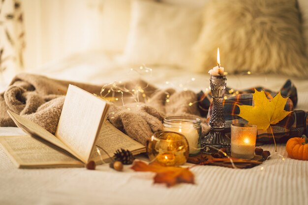 Suéteres e velas com decoração de outono e livro para ler detalhes de natureza morta no interior da casa