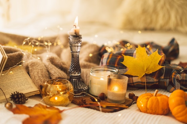 Suéteres e velas com decoração de outono e livro para ler detalhes de natureza morta no interior da casa