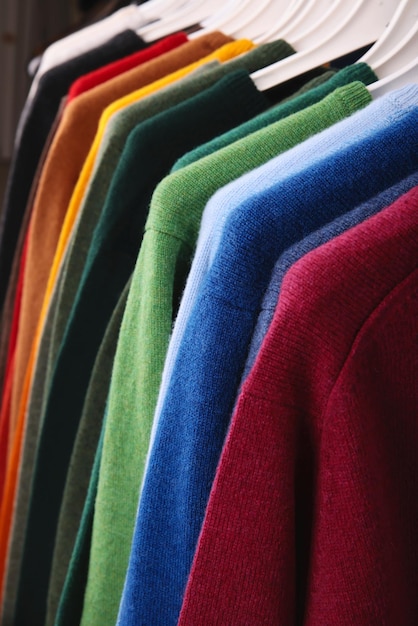 Suéteres quentes roupas de outono e inverno prateleira de metal com vários suéteres em cabides colocados na moda moderna boutique indústria leve