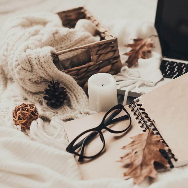 Suéteres y taza de té con cuaderno, computadora portátil y ropa de tejer