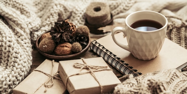 Suéteres y taza de té con cuaderno, vela y ropa de tejer